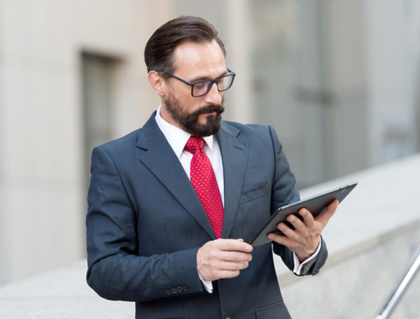 Man in a business suit looking at a tablet.