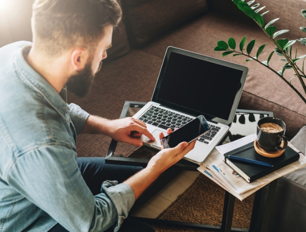 Man sitting at a table with his laptop and phone.